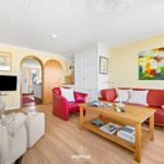 Living room with red sofa, wooden table, and TV on the wall.