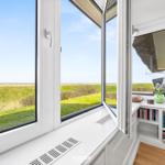 Wide view through large window onto green fields and sky.