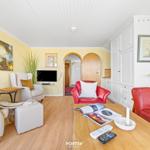 Living room with red sofa, white armchairs, and wooden floor.