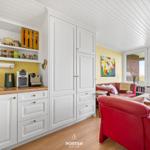 Living area with red sofa, kitchenette, and view of the field.