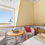 Bedroom with field view, two armchairs, table, and bed.