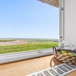 Through the window, you can see a green meadow and the sea.