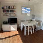 Esszimmer mit Tisch, Stühlen und Fenster. Fernseher und Bücherregale an der Wand.