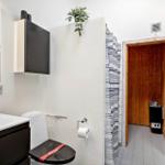 Badezimmer mit Toilette, Waschbecken und Dusche. Sauna im Hintergrund.