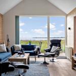 Wohnzimmer mit Blick auf die Landschaft. Holzwände, Sofa, Sessel und Fernseher.