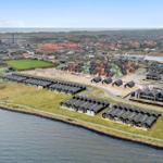 Uferpromenade mit modernen Häusern und Blick auf die Stadt und das Meer.