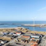 Meer, Windkraftanlagen und Hafenbereich mit Gebäuden und Straßen