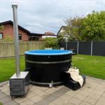 Hochwertiger Whirlpool mit Holzrahmen und Heizung im Garten. Grünfläche und Sitzgelegenheiten.