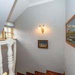 Hausflur mit Treppenhaus, Wandbeleuchtung und Bildern an der Wand.