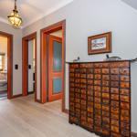 Flur mit Holzboden, roten Türen und antikem Schrank mit vielen Schubladen.