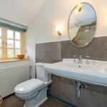Badezimmer mit Toilette, Waschbecken und Fenster mit Blick auf Grün.