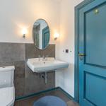 Badezimmer mit Toilette, Waschbecken und blauer Tür.