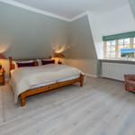 Schlafzimmer mit Dachschrägen, Bett, Nachttisch, Sessel und Fenster.