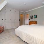 Schlafzimmer mit Dachschräge, Bett, Kleiderschrank und Sessel.