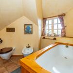Bad mit Holzbadewanne, Toilette und Bidet unter schrägen Decken.
