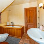 Badezimmer mit Holzbadewanne, Waschbecken und Spiegel
