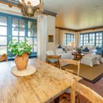 Esszimmer mit Holztisch und Stühlen. Wohnbereich mit Sofa, Couchtisch und Fenstern.