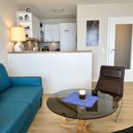 Blauer Sofa mit orangefarbenen Kissen, runder Tisch und braune Sitzgelegenheit.