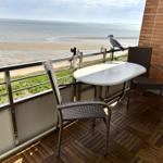 Terrasse mit Tisch und zwei Stühlen, Blick auf Strand und Meer.