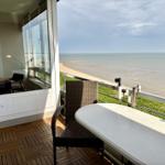 Terrasse mit Tisch und Stühlen. Blick auf Strand und Meer.