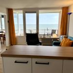 Wohnraum mit Blick aufs Meer, Sofa, Sessel und Kücheninsel.