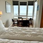 Schlafzimmer mit Blick aufs Meer und Essbereich mit Tisch und Stühlen.