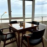 Esszimmer mit Blick aufs Meer und Holztisch mit vier Stühlen.