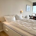 Schlafzimmer mit Bett, Tisch und Meerblick.