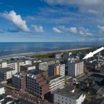 Aussicht auf Strand und Stadt mit weißen Gebäuden und blauem Himmel.