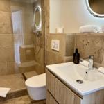 Bad mit Dusche, Waschbecken und Toilette. Steinwand und Holzschrank.