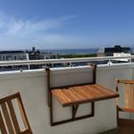 Terrasse mit Holztisch und Stühlen, Blick auf Meer und Stadt