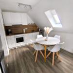 Küche mit Essbereich unter Dachschrägen, weißer Tisch, vier Stühle, Dachfenster.