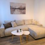 Ein Wohnzimmer mit Ecksofa, zwei runden Tischen und Wandbild.