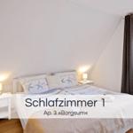 Schlafzimmer mit Doppelbett, zwei Nachttischen und Fenster mit Blick auf Wald.