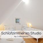 Zwei Betten mit Starfish-Bettwäsche, kleines Fenster, weiße Nachttische und Holzboden.