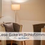 Lese-Ecke mit zwei Stühlen und Tisch im Schlafzimmer. Stehlicht und Fenster sichtbar.