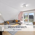 Wohnbereich mit Sofa, Sessel und Terrasse. Holzboden und Schiebetür.