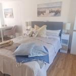 Schlafzimmer mit Bett, Nachttischen und Schreibtisch. Wandbilder zeigen Strandlandschaften.