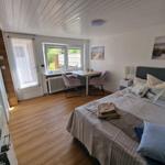 Schlafzimmer mit Bett, Schreibtisch und Fenster zur Außenterrasse.