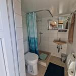 Badezimmer mit Dusche, Waschbecken und Toilette. Türkisfarbener Duschvorhang.