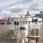 Balcony with table, chairs, and view of rooftops and a tower.