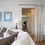 Wohnzimmer mit Sofa, Lampen und Blick in die Küche.