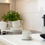 Küche mit Kaffeemaschine, Tasse und Pflanze auf Arbeitsfläche.