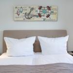 Doppelbett mit weißen Kissen und Wandbild mit Segelthema.