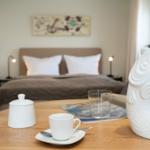 Ein Bett mit weißen Kissen und ein runder Tisch mit einer weißen Teekanne.