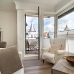 Wohnzimmer mit Blick auf Dachgasträume und Balkon mit Sitzgelegenheit.