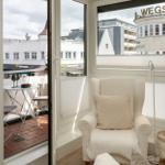Raum mit Sessel und Balkon, Blick auf Gebäude mit Schild.