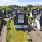 Dorfhaus mit Garten und Terrasse. Umgeben von Bäumen und gepflegten Rasenflächen.