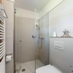 Dusche mit Glaswand, Toilette und Heizkörper an der Wand.