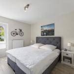 Schlafzimmer mit Doppelbett, Nachttisch und Fenster zur grünen Aussicht.